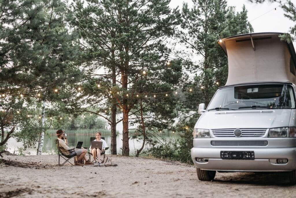 Homeoffice im Wohnmobil Paar am See mit Laptops